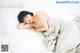 A naked woman laying on a bed covered in a blanket.