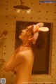 A naked woman taking a shower with a bunny hat on her head.