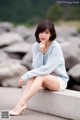 A woman sitting on a concrete ledge with her legs crossed.