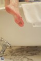 A woman's feet in a bathtub with a towel on the edge.