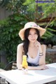 A woman sitting at a table with a straw hat on.