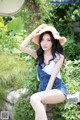 A woman in a straw hat sitting on a stone wall.