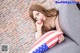 A woman sitting on a couch holding an American flag pillow.