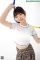 A woman in a white shirt and plaid skirt holding a blue hula hoop.