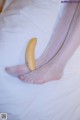 A banana sitting on top of a bed next to a woman's feet.