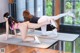 A woman in a pink bikini and white leggings doing a yoga pose.