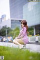 A woman in a pink dress crouching on the ground.