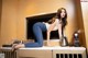 A woman sitting on top of a counter next to a coffee maker.