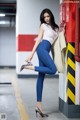 A woman leaning against a red fire hydrant in a parking garage.