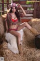 A woman in a cowboy outfit sitting on a pile of hay.