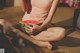 A woman sitting on the floor holding a watermelon.