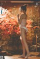 A woman in a pink tank top and white panties standing on a wooden deck.