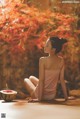 A woman sitting on a wooden table with a bowl of watermelon.