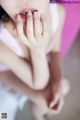 A woman in a pink tank top holding her hands to her mouth.