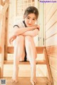 A woman sitting on a wooden staircase with her legs crossed.