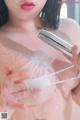 A woman is taking a shower with a shower head.