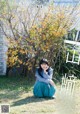 A woman sitting on the ground in front of a tree.