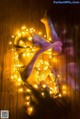 A naked woman laying on a wooden floor covered in lights.