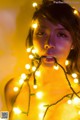 A woman holding a string of lights in her mouth.