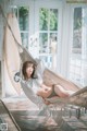 A woman laying in a hammock with a surfboard in the background.