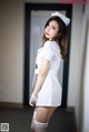 A woman in a white nurse outfit posing for a picture.