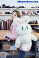 A woman holding a large white stuffed animal in a store.