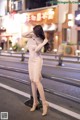 A woman in a pink dress standing on a city street.