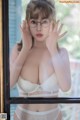 A woman wearing glasses is posing in front of a window.