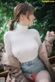 A woman in a white top and denim shorts sitting on a bench.