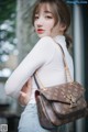 A woman holding a brown louis vuitton bag in her hand.