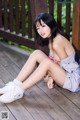 A woman sitting on a wooden deck with her legs crossed.