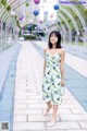 A woman in a white dress standing on a sidewalk.