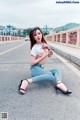 A woman sitting on the side of a road with her legs crossed.