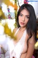 A woman in a white lingerie posing in front of a Christmas tree.