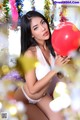 A woman in a white lingerie holding a red balloon.