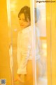 A woman in a white shirt is standing in front of a glass door.