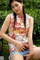 A woman in a cheongsam sitting on a bench in the grass.