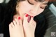 A woman with long black hair and red fingernails licking her toes.