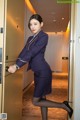 A woman in a blue suit is opening a door.