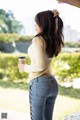 A woman in jeans and a sweater holding a cup of coffee.