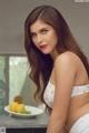 A woman in a white bikini sitting on a kitchen counter.