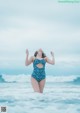 A woman in a blue and white bathing suit standing in the ocean.