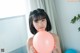 A young woman holding a pink balloon in her hands.