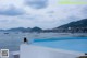 A woman standing on the edge of a swimming pool next to the ocean.