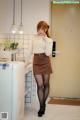 A woman standing in a kitchen next to a refrigerator.