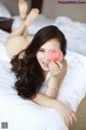 A woman laying on a bed holding an apple.