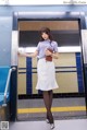 A woman in a white skirt is standing in a subway station.