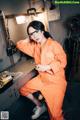 A woman in an orange jumpsuit sitting at a table.