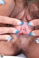 A woman with blue fingernails is holding her hairy pussy.