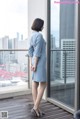 A woman standing on a balcony looking out a window.